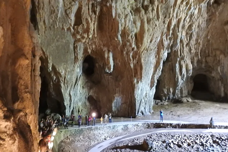 Path through a vast illuminated chamber in the Škocjan Caves